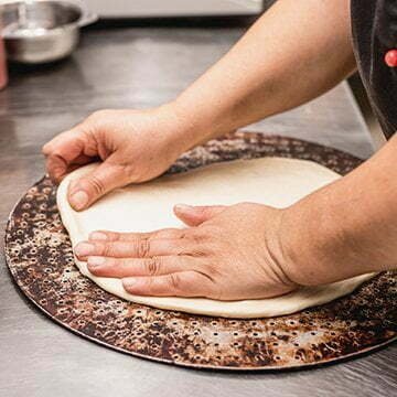 Man hand stretching pizza dough